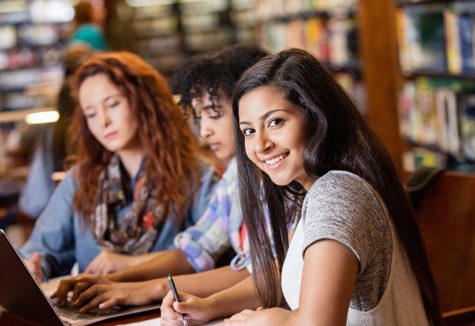 three high-school girls studying in their school library.