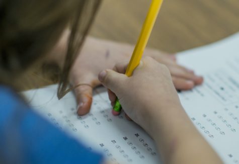 A young student erasing an answer from a standardized testing answer sheet.