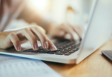 Female hands typing on a laptop.