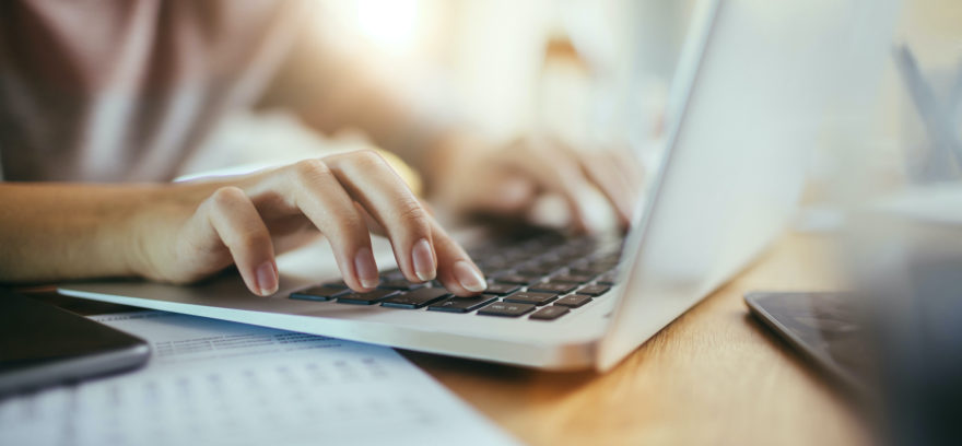 Female hands typing on a laptop.