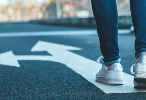 A woman walking on a path with an arrow pointing both forward and to the left.