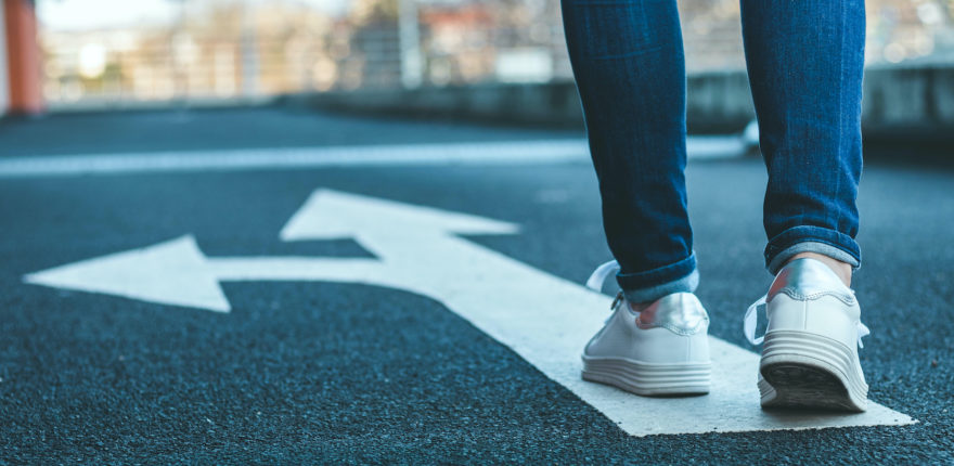 A woman walking on a path with an arrow pointing both forward and to the left.