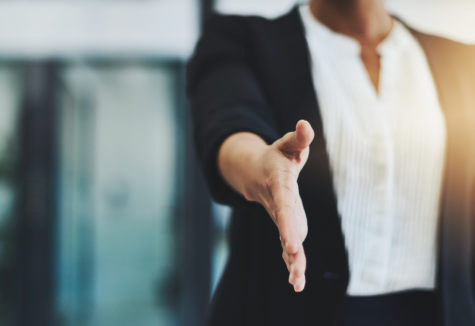 A professional businesswoman extending her hand.