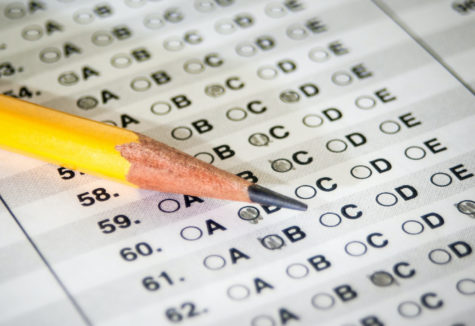 A closeup image of a pencil laying on a multiple-choice answer form.