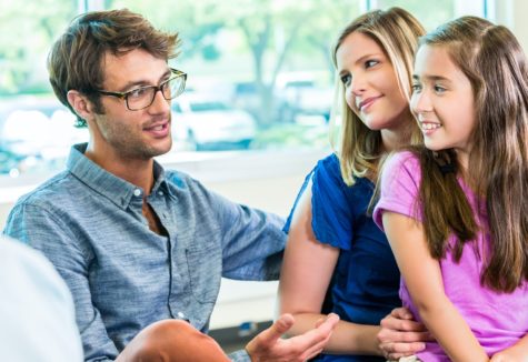 A couple and their young daughter sitting and talking with a consultant.