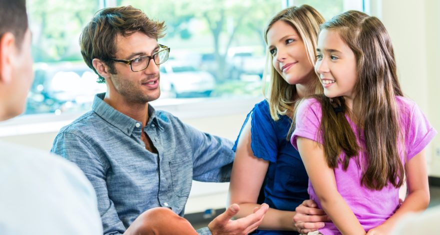 A couple and their young daughter sitting and talking with a consultant.