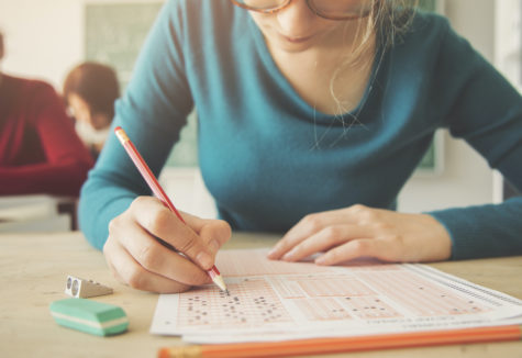 A female student at her school desk taking a test on a scantron form.