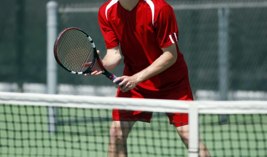 A man playing tennis up close to the net.