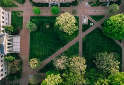 An overhead view of a set of walkways cutting through a grassy quad between several large university buildings.