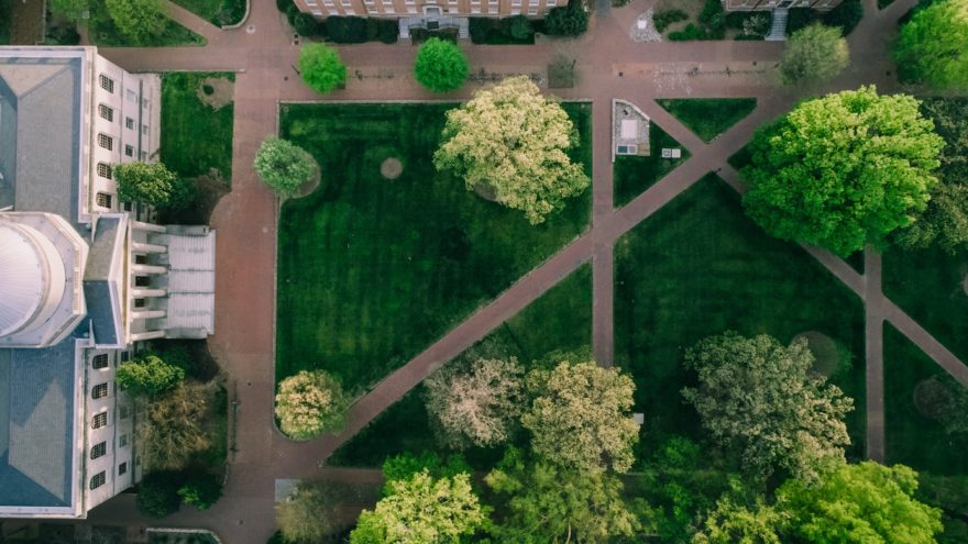 An overhead view of a set of walkways cutting through a grassy quad between several large university buildings.