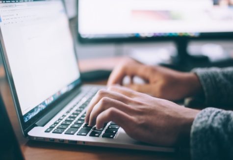 Hands typing on a laptop computer.